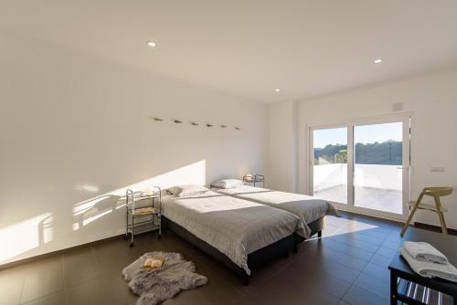 a white bedroom with a bed and a large window at Vakantiehuis Zilverkust Portugal 