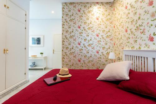 sypialnia z czerwonym łóżkiem z kapeluszem w obiekcie Sevilla Central Suites Apartamentos Puerta Jerez w Sewilli