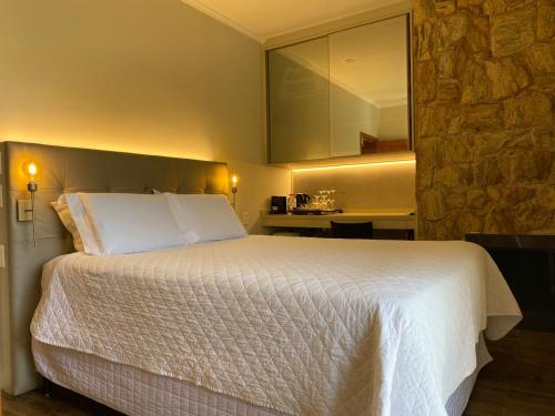 a bedroom with a large white bed with a stone wall at Locanda Montecielo - Vale dos Vinhedos in Bento Gonçalves