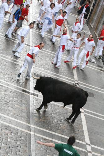 a crowd of people running down a street with a bull at Gran Hotel La Perla in Pamplona