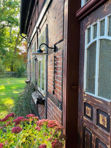 a brick building with a door and some flowers at Wendlandhof Lüggau in Dannenberg