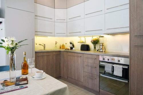 una cocina con armarios blancos y una mesa con una botella de vino en Velem Spirit Apartment en Velem