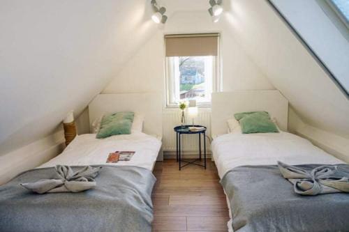two beds in a attic room with a window at Velem Spirit Apartment in Velem