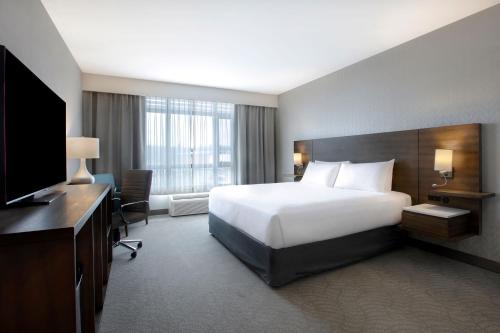 a hotel room with a bed and a television at Great Blue Heron Hotel in Port Perry