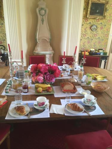 a wooden table with food and flowers on it at Chambres d'hôtes & Gîtes du Château de Grand Rullecourt in Grand Rullecourt