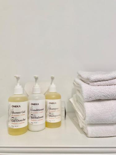 three bottles of sunscreen sitting on a shelf next to towels at Beatnik Hotel in Bromont