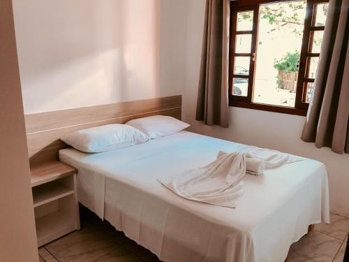 um quarto com uma cama branca com janela em Pousada Moçambique em Florianópolis