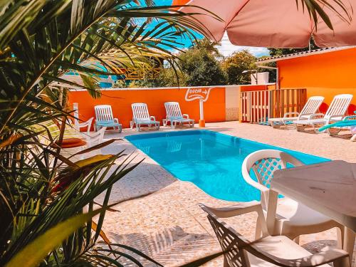 uma piscina com cadeiras, uma mesa e um guarda-sol em Pousada Moçambique em Florianópolis