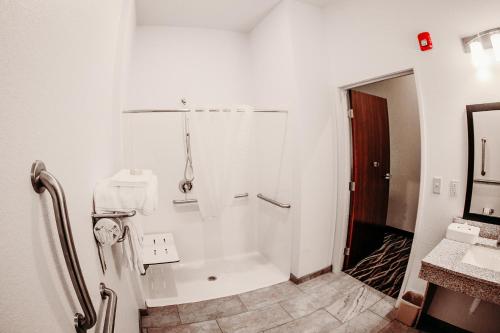 a white bathroom with a shower and a sink at Cobblestone Hotel & Suites International Falls in International Falls