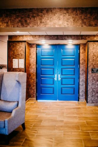 a blue door in a room with a chair at Cobblestone Hotel & Suites International Falls in International Falls