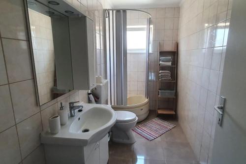 La salle de bains est pourvue d'un lavabo, de toilettes et d'un miroir. dans l'établissement Apartment Divine Metković72m2, à Metković