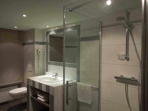 a bathroom with a shower and a sink and a toilet at Hôtel Saint-Pierre in Pontarlier