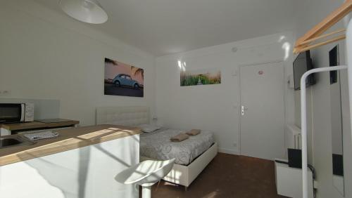 a small white room with a bed and a kitchen at Studio proche de la mer in La Baule