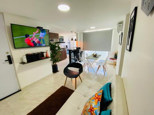a living room with a couch and a tv on a wall at Apartamento Exclusivo - Caribe Campestre Coveñas in Coveñas
