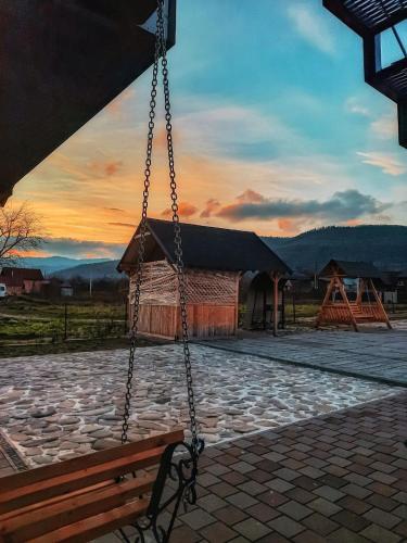 a swing in front of a building with a sunset at Villa Opir in Skole