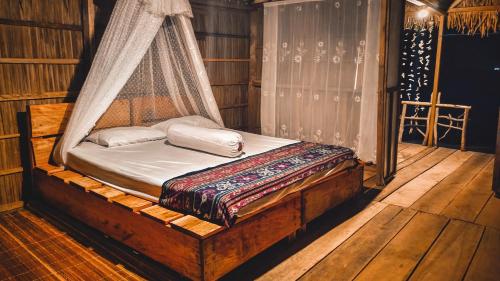 Cama en habitación con mosquitera en Kamar Raja GuestHouse en Selpele