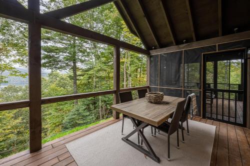 a dining room with a table and chairs on a deck at stayNantahala - Smoky Mountain Cabins in Aquone