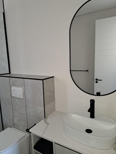 a white bathroom with a sink and a mirror at The Marlo Apartment in Cape Town