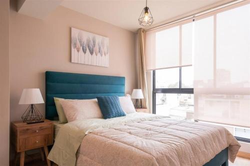 - une chambre avec un lit doté d'une tête de lit bleue et d'une fenêtre dans l'établissement Elegant&Modern Apt in San Isidro, à Lima
