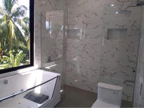 a white bathroom with a toilet and a window at Taylors Country Home by Taylors Traveller's Inn- The Grande Second Floor in Catarman