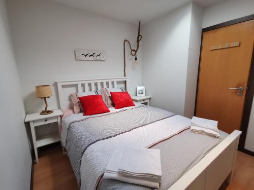 een slaapkamer met een groot bed met rode kussens bij Casa na onda Liberdade in Nazaré
