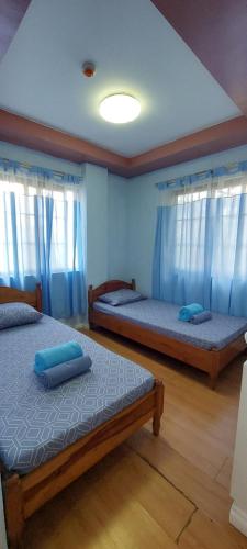 two beds in a room with blue curtains at Koinonia Retreat CenteR in Baguio
