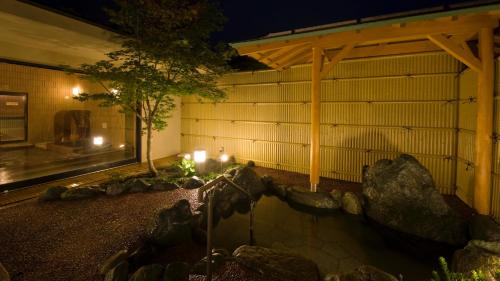 un edificio con un estanque delante de él por la noche en 富士山の見える全室個室サウナ付旅館 しずく en Yamanakako
