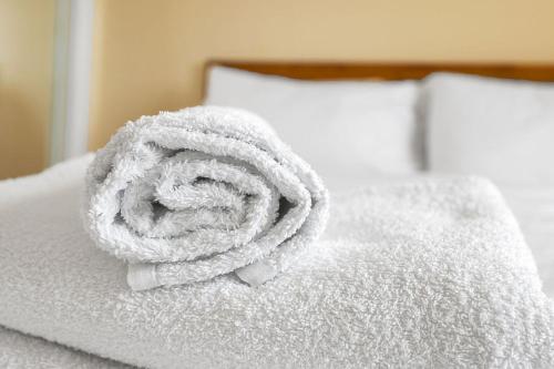 un rollo de toallas blancas en una cama en Modern 1BR flat - free parking + lift en Edimburgo