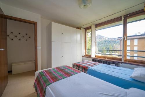 a bedroom with two beds and a large window at Appartamento con Vista! A Due Passi dalle Piste in Madonna di Campiglio