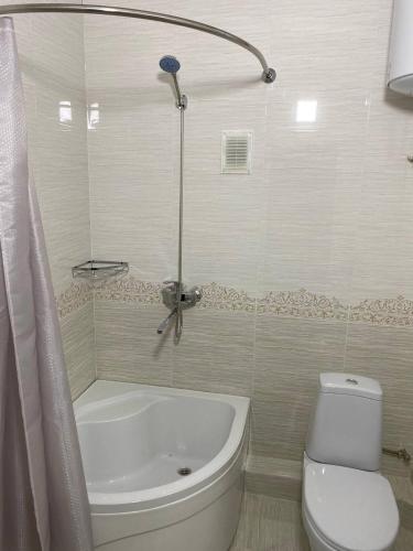 a bathroom with a white tub and a toilet at GREEN APPLE GUEST House in Tashkent