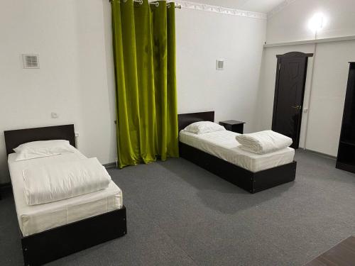 two beds in a room with green curtains at GREEN APPLE GUEST House in Tashkent