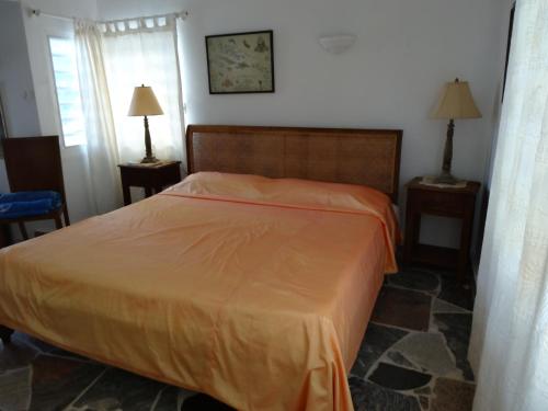 1 dormitorio con 1 cama con manta naranja en Villa LAGUNA, en Lowlands