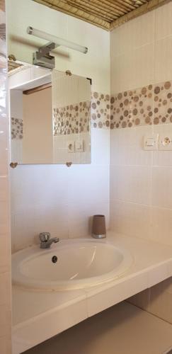 uma casa de banho branca com um lavatório e um espelho em Résidence Safari Village em Saly Portudal