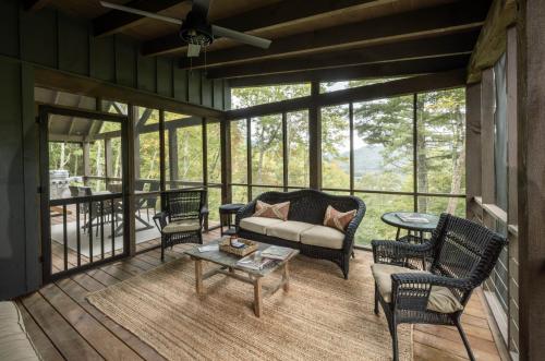 a screened in porch with a couch and chairs at stayNantahala - Smoky Mountain Cabins in Aquone