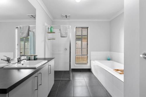 a white bathroom with a sink and a tub at Summer Breeze - 10 mins to Barwon Heads & Torquay! in Mount Duneed