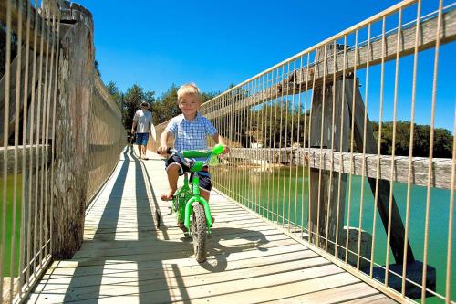 a young boy riding a bike across a bridge at Valla Beach Holiday Park in Valla Beach