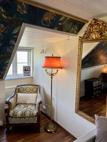 a room with a lamp and a chair and a mirror at Sydkustens at Pillehill in Skivarp