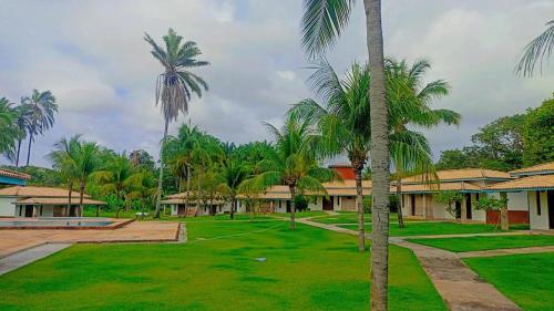 um resort com palmeiras e um quintal verde em Eco Pousada côco dendê em Itacimirim