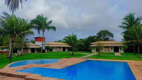uma piscina em frente a uma casa com palmeiras em Eco Pousada côco dendê em Itacimirim