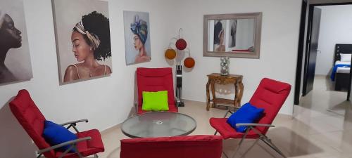 una stanza con sedie rosse e un tavolo in vetro di La Marina -Apartamentos frente al mar a Ríohacha