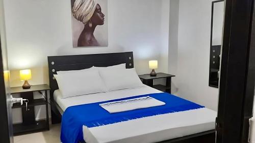 a bedroom with a bed with a blue and white blanket at La Marina -Apartamentos frente al mar in Ríohacha