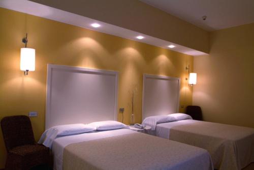 two beds in a hotel room with lights on the wall at Hotel Globo in Formigine