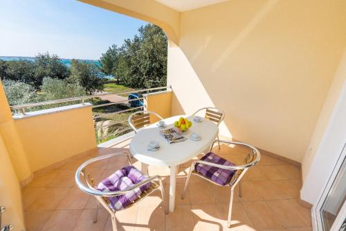 Elle comprend un petit balcon avec une table et des chaises blanches. dans l'établissement Apartment Vrsi - Mulo 5951d, à Vrsi