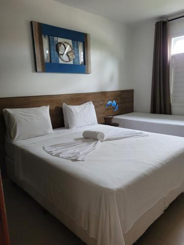 een slaapkamer met een groot wit bed en een raam bij Boulevard da Praia 124 B in Porto Seguro