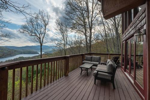 a deck with chairs and a table on a house at stayNantahala - Smoky Mountain Cabins in Aquone