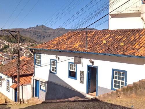 une maison blanche avec une porte bleue et des montagnes en arrière-plan dans l'établissement Suíte em Hospedaria no Centro Histórico, à Ouro Preto