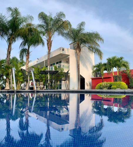 a house with palm trees and a swimming pool at Hotel Cascada in Cuautla Morelos
