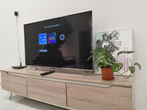 a large flat screen tv sitting on top of a dresser at Flora Homestay in Taman Flora in Batu Pahat
