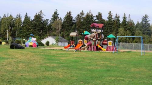 a park with a playground with slides and a play equipment at Boardwalk RV Rental Site #19 in Cavendish