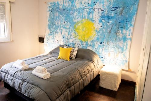 1 dormitorio con 1 cama con una pintura en la pared en Casona alegre con jacuzzi en Luján. Argentina en Luján